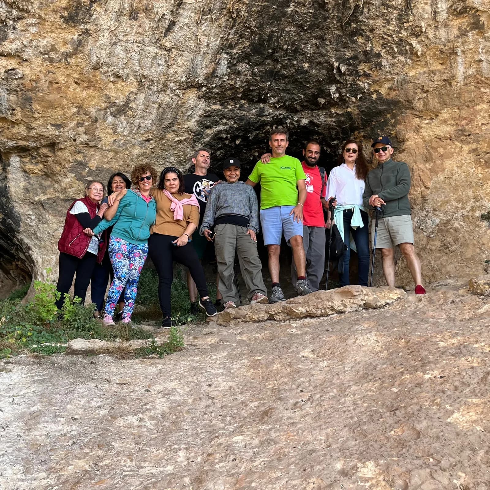 Grupo de personas junto a una pared de roca.